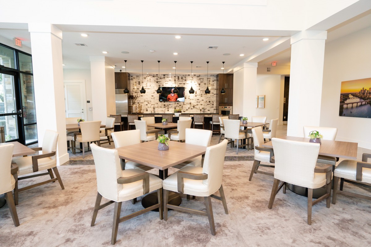 A modern dining area with neatly arranged tables and chairs, featuring stylish lighting and contemporary decor.