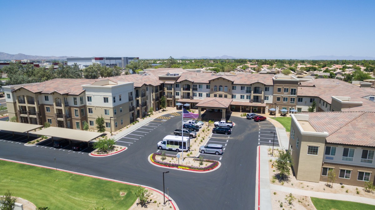 Aerial view of a modern building with a parking lot and landscaped surroundings.