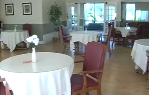 A spacious dining area featuring empty tables and elegant furnishings, with natural light streaming in.