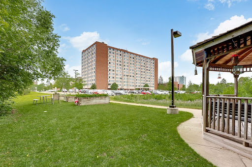 A view of a residential apartment building surrounded by green grass and trees in an urban setting.