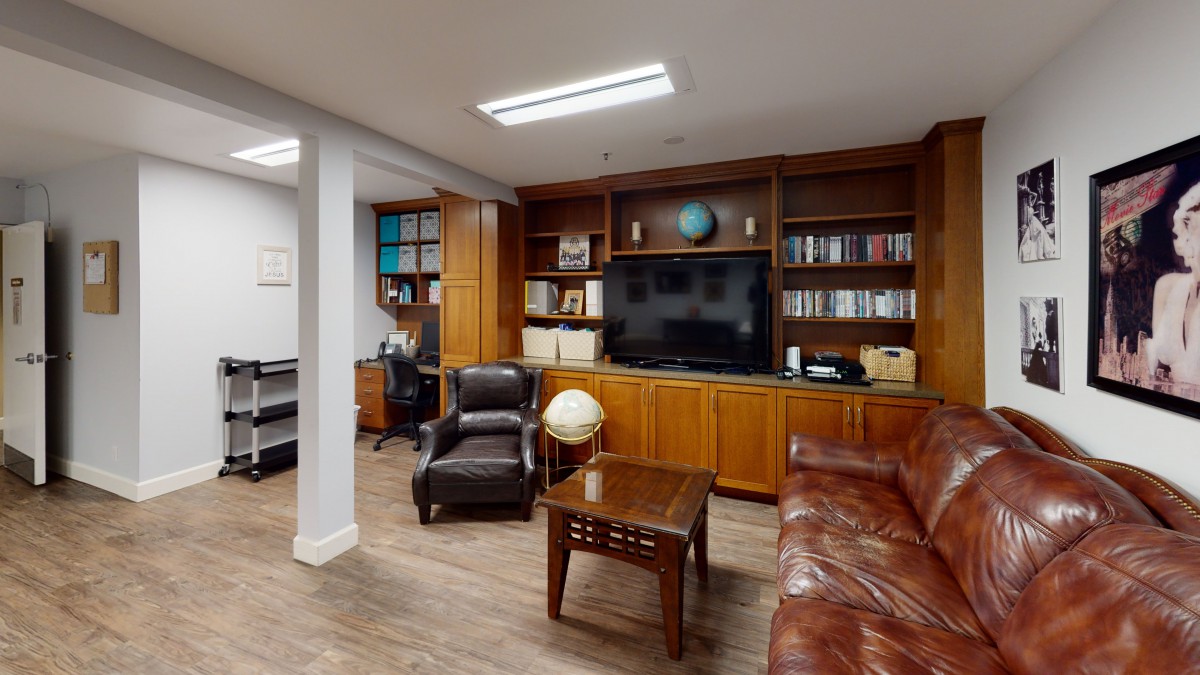 A cozy library office with a leather sofa, armchair, bookshelves, and a globe.