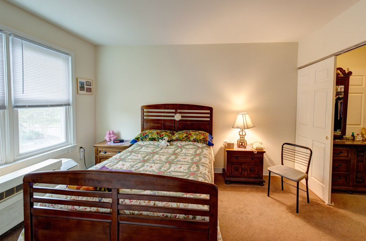 A cozy bedroom with a wooden bed, bedside table, and a lamp.