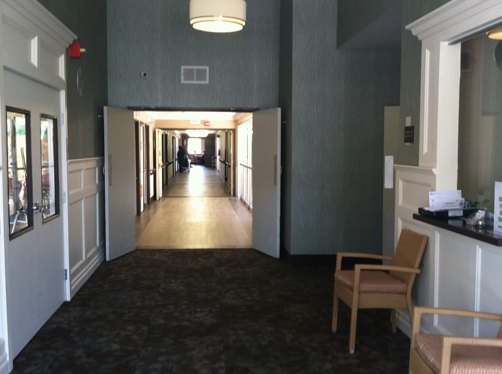 A well-lit hallway with open doors and a single chair placed to the side.