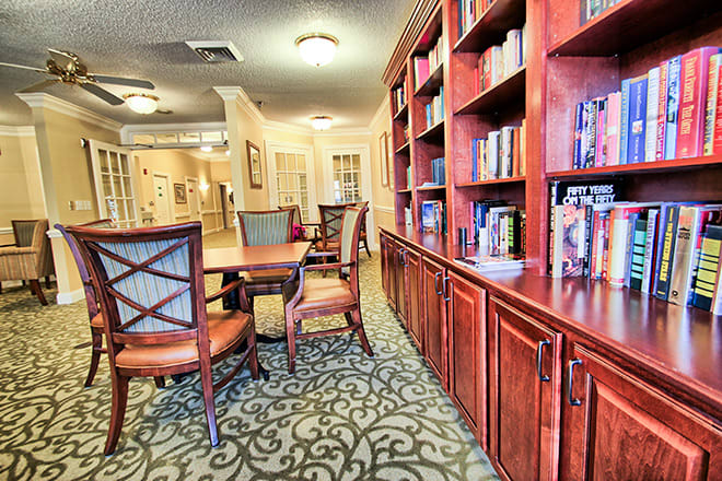 A cozy library setting with wooden bookshelves and a table surrounded by chairs.