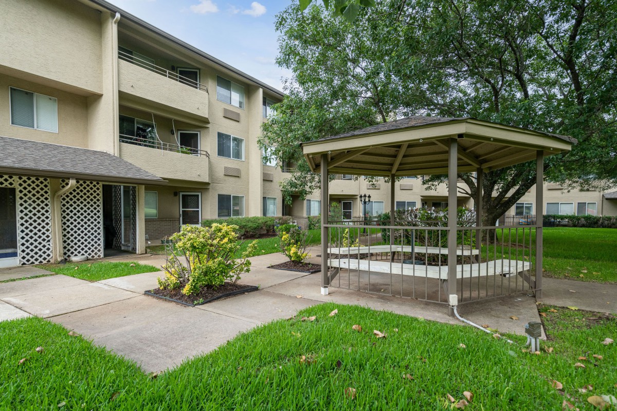 An apartment complex with a gazebo and well-maintained green lawn.