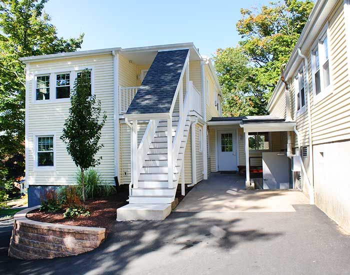 A two-story residential house with exterior stairs and a driveway.