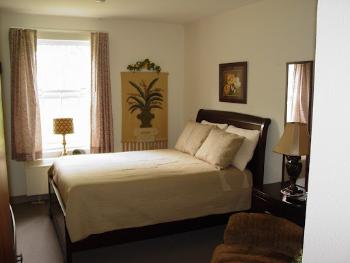 A cozy and inviting bedroom featuring a neatly made bed, decorative artwork, and warm lighting.