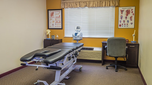 An organized medical office featuring a treatment table and a work desk.