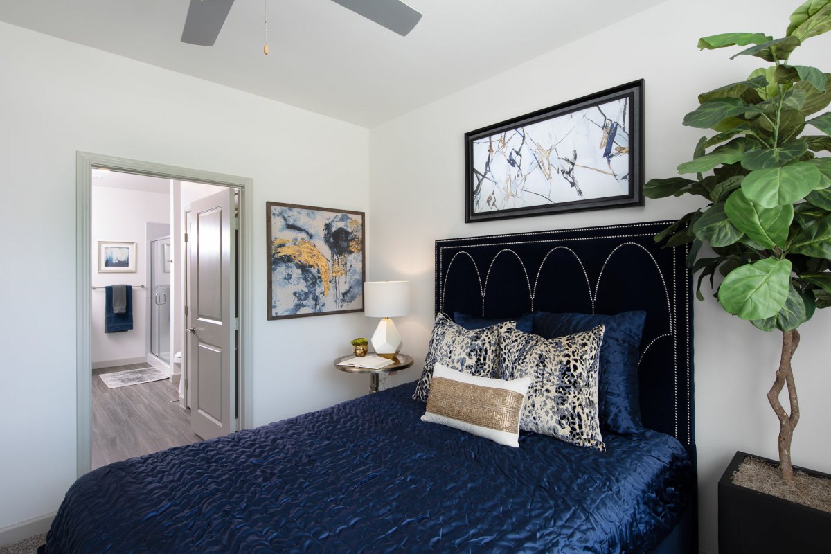 A stylish bedroom featuring a navy blue bedspread, decorative pillows, and contemporary artwork.