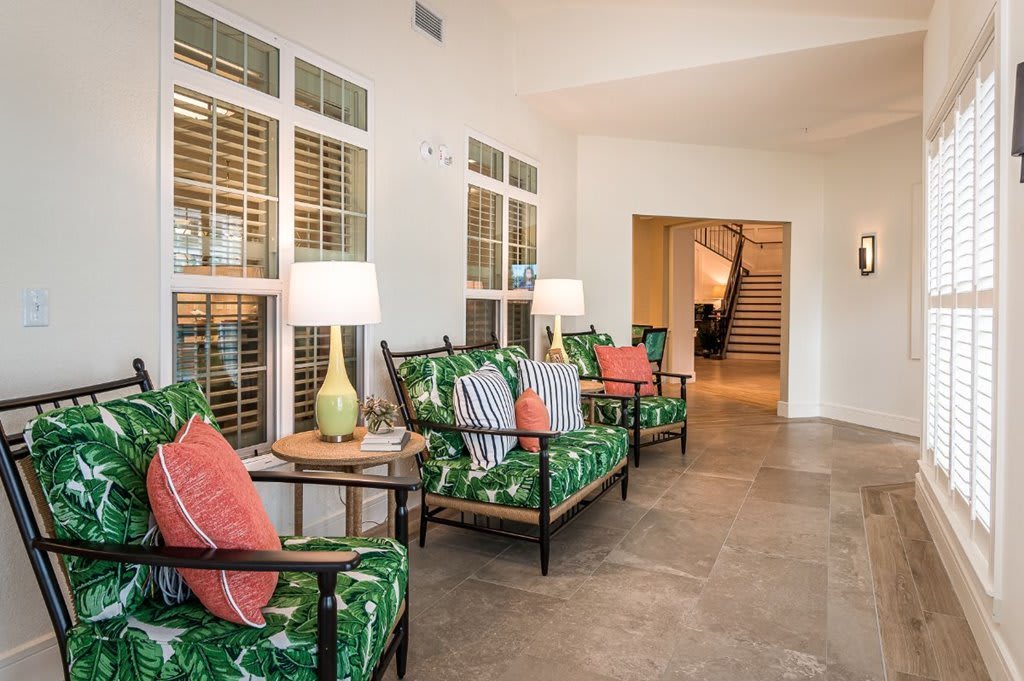 A cozy living room with green patterned chairs, accent pillows, and warm lighting.