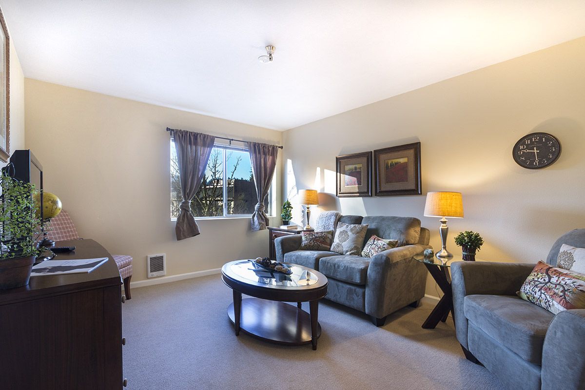 A cozy living room with modern decor, featuring a sofa, coffee table, and ample natural light.