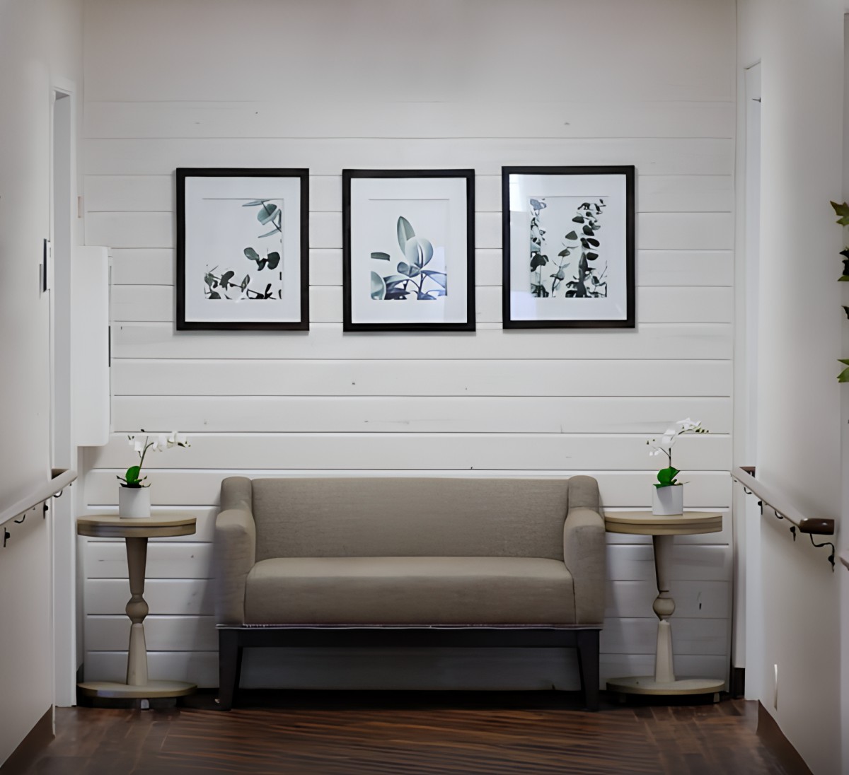 A neatly arranged waiting area with a sofa, side tables, and framed wall art.