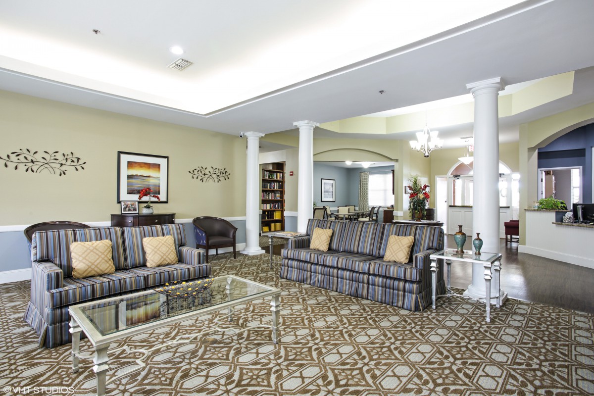 A spacious and elegantly designed living room with comfortable sofas, a central coffee table, decorative columns, and wall art.