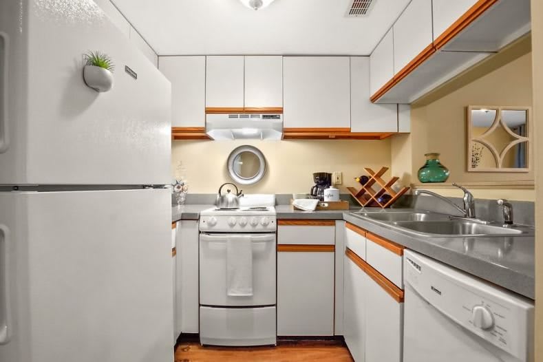 A compact kitchen with white cabinets, a stove, and a refrigerator.