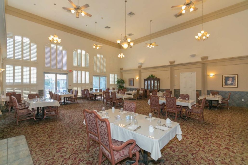 An elegant dining room with high ceilings, adorned with chandeliers and neatly arranged tables and chairs.