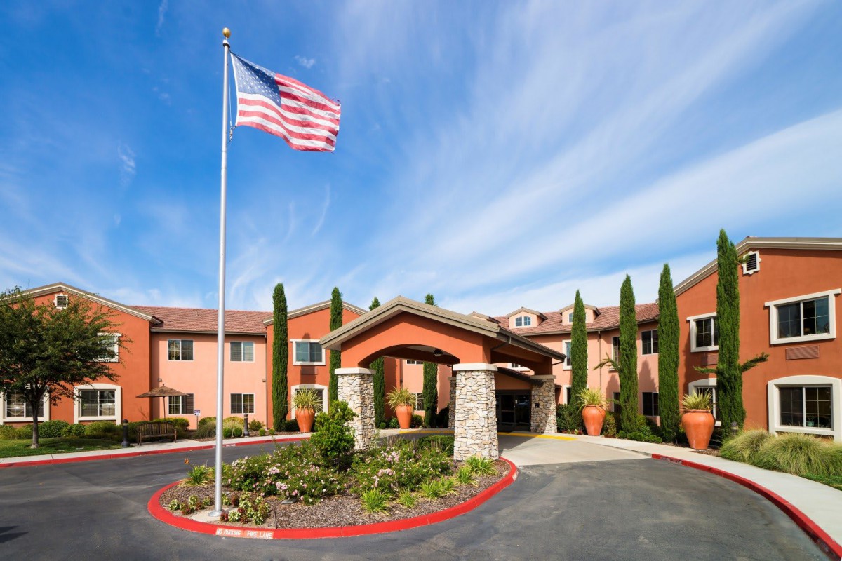 A building entrance with a prominent American flag and landscaped surroundings.