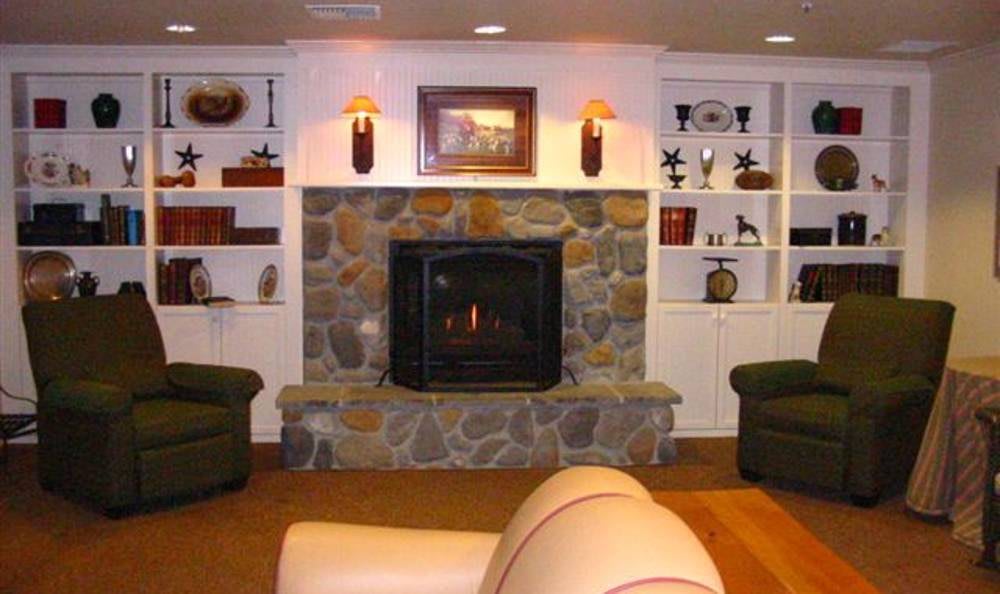 A cozy living room featuring a stone fireplace and surrounding shelves with decor.
