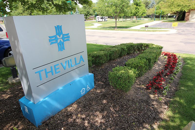 A decorative sign for 'The Villa' surrounded by landscaped gardens.