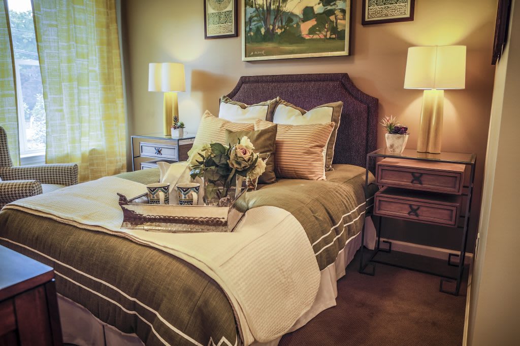 A cozy and well-decorated bedroom with a neatly made bed, lamps, and elegant furnishings.