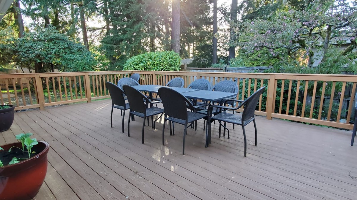 A patio set with a table and chairs on a wooden deck surrounded by trees.