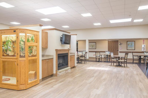 A spacious and inviting common area featuring a fireplace, dining tables, and natural light.