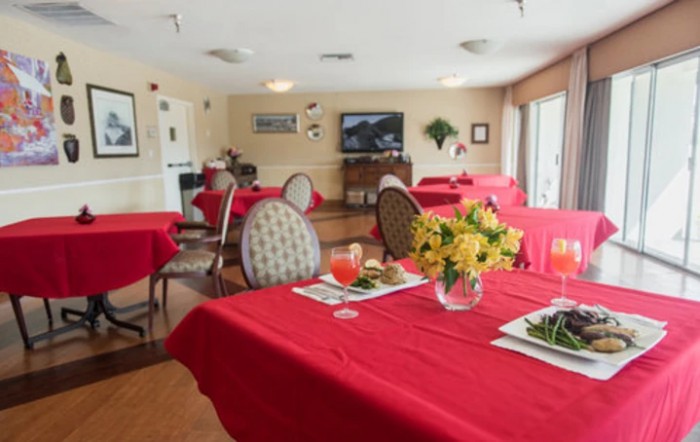 A cozy dining room with tables covered in red tablecloths, set with meals and floral centerpieces.