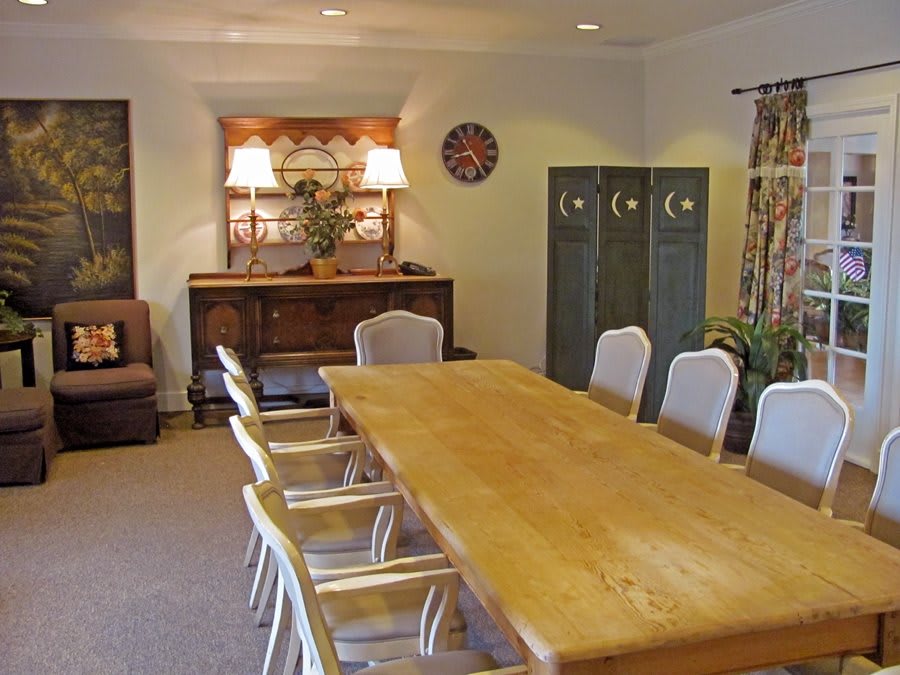 A conference room with a large wooden table and chairs, featuring decorative elements and a cabinet.