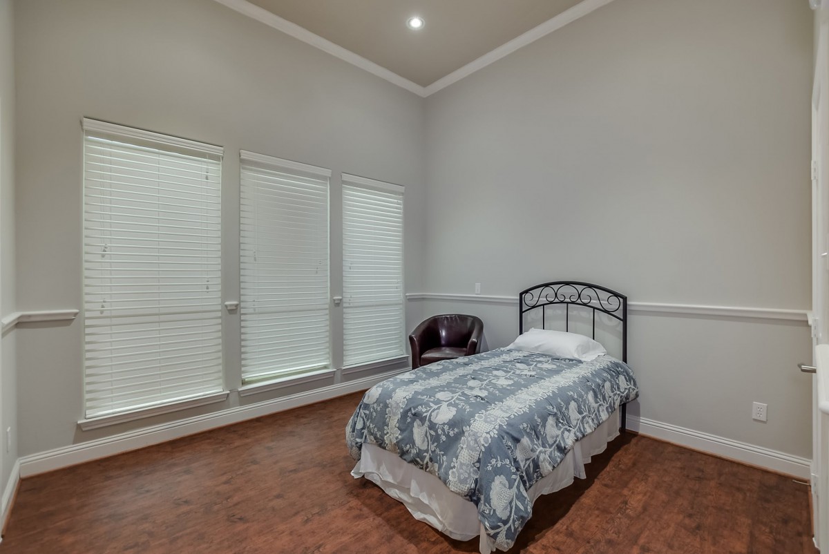 A minimalist bedroom with a single bed, chair, and large windows.