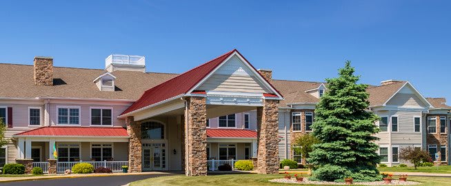 A residential-style building with a red roof and stone facade, featuring a welcoming entrance and well-maintained landscaping.