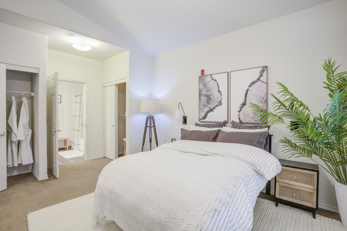 A minimalist bedroom with white bedding and modern decor.