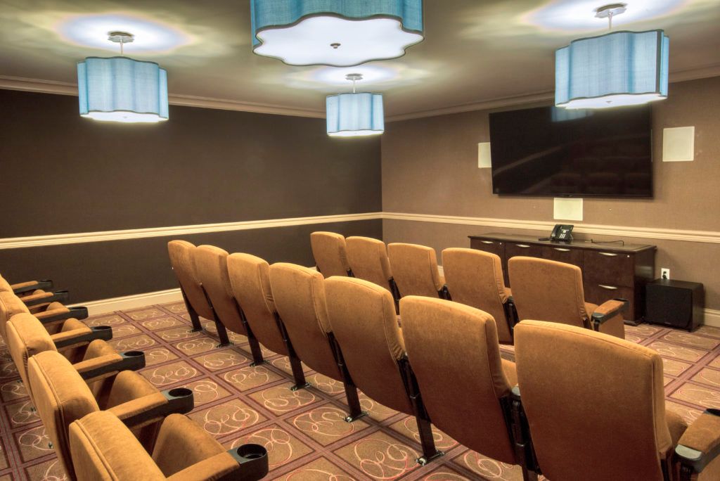 A small, cozy theater room with rows of cushioned seats and a large screen at the front.