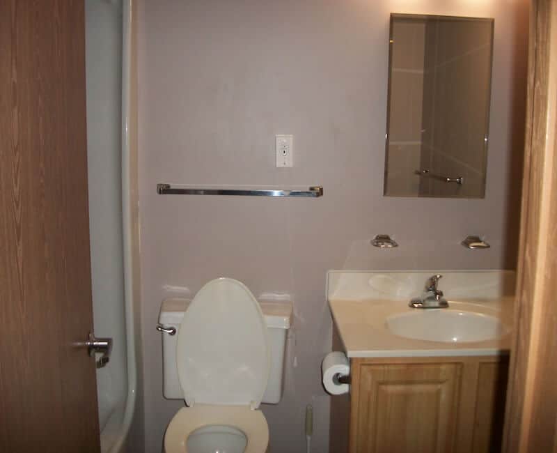 A small bathroom featuring a toilet, sink, and mirror.