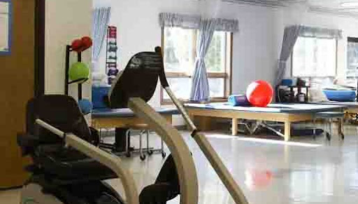 A glimpse of a fitness space equipped for rehabilitation, featuring exercise equipment and colorful exercise balls.