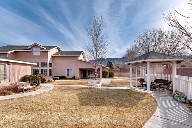 A spacious backyard featuring a large house, a gazebo, and a well-maintained lawn under a clear blue sky.