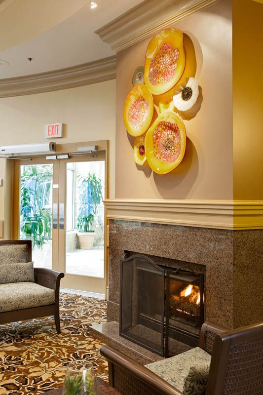 A cozy lobby area with a fireplace, artistic wall decor, and comfortable seating.