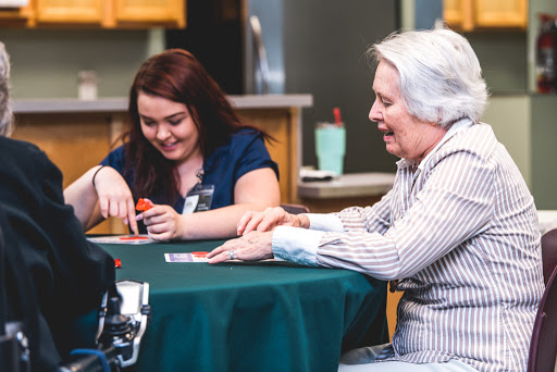 A caregiver and an elderly woman enjoying a card game together, fostering connection and joy.