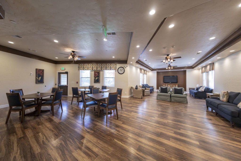 A spacious interior living room with tables, chairs, and a wooden floor.