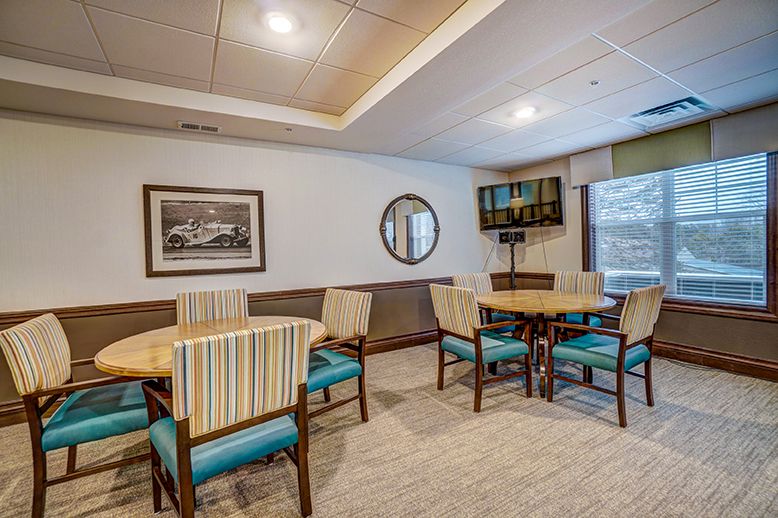 A modern dining area with tables, chairs, and a wall-mounted TV.