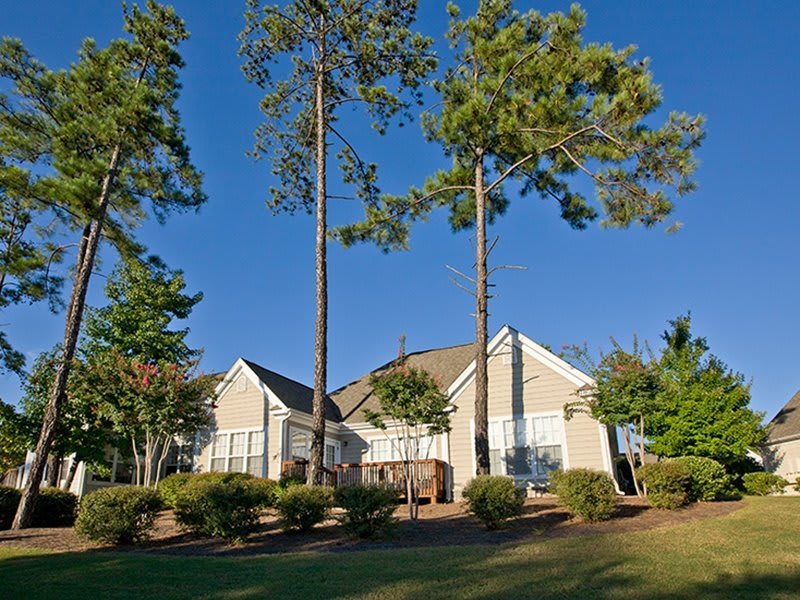 A suburban house surrounded by tall trees and a well-maintained lawn.