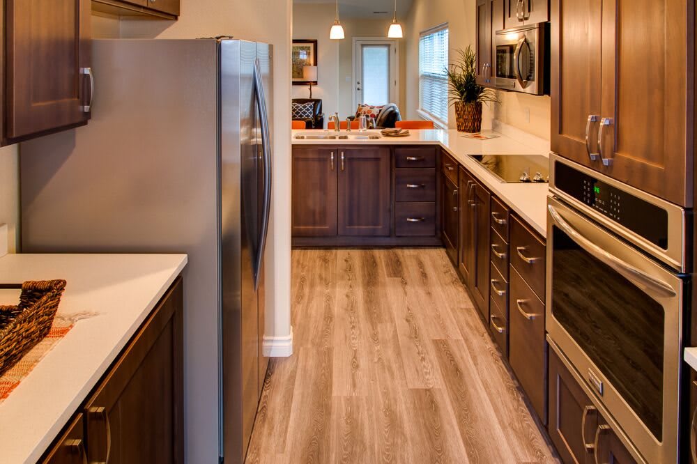 A modern kitchen with wooden cabinets, stainless steel appliances, and a hardwood floor.