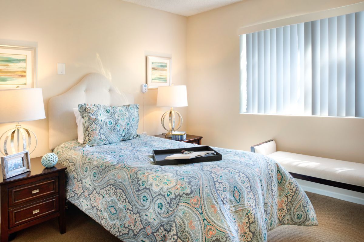 A cozy bedroom with a single bed, bedside table, and a window.