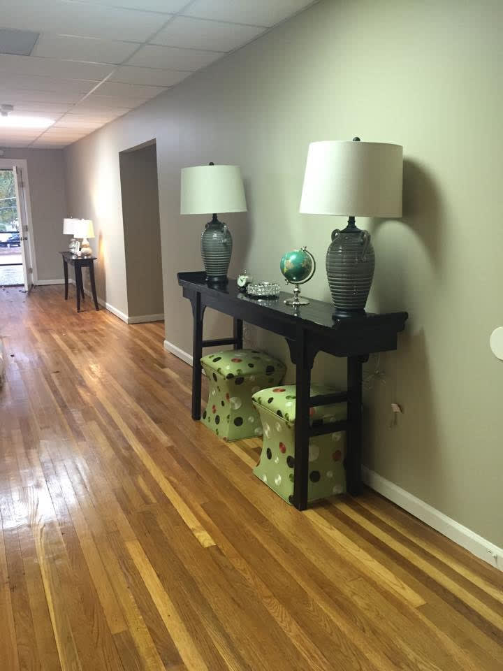 A modern hallway with wooden flooring, featuring a console table adorned with lamps and decorative accents.