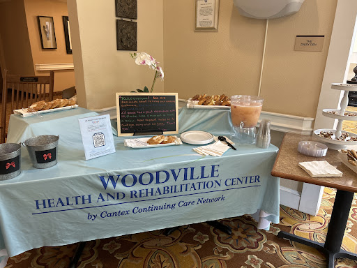 A welcoming setup for the Woodville Health and Rehabilitation Center at a community event, featuring snacks and informational materials.