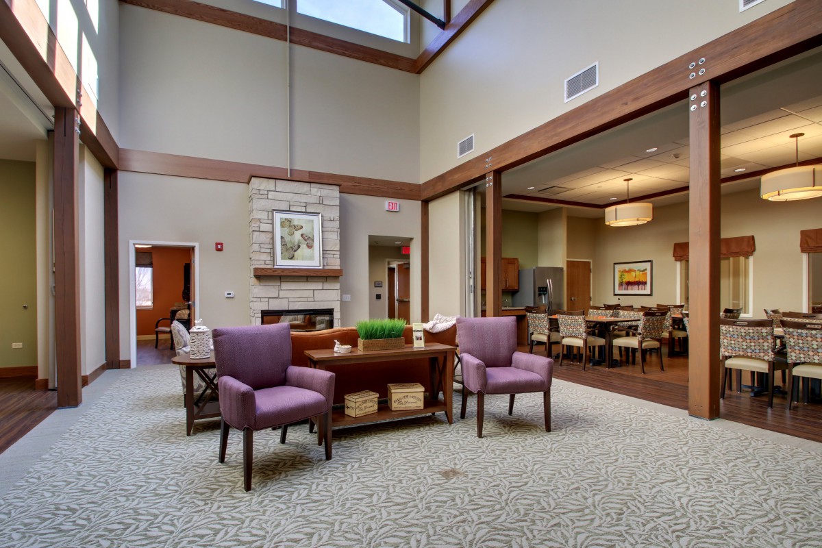 A modern lounge area with comfortable seating and a central fireplace, featuring large windows for natural light.