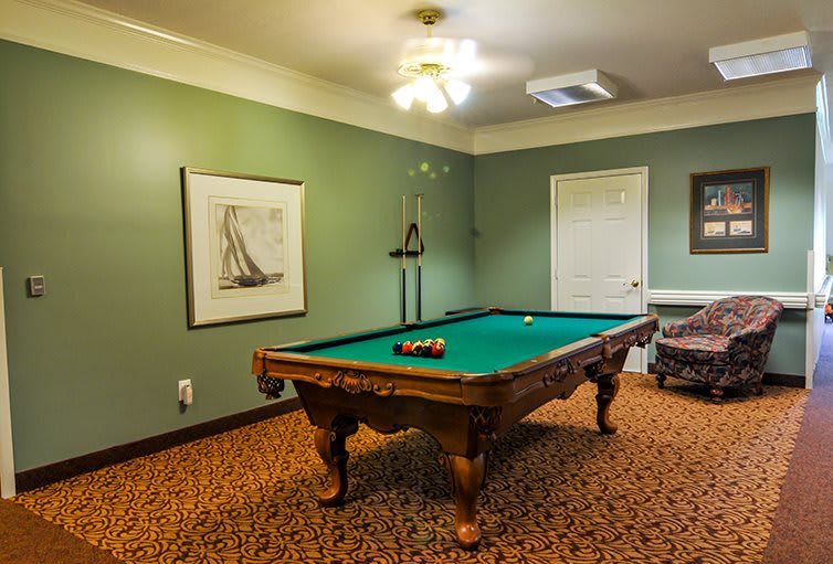 A cozy game room featuring a classic billiards table with green felt, surrounded by walls adorned with artwork.