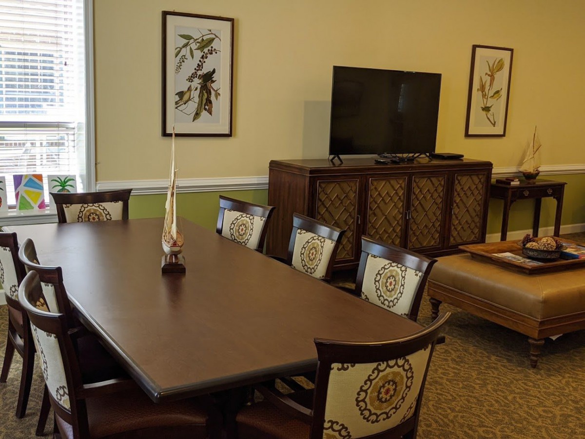 A cozy dining room featuring a wooden dining table with chairs, a television on a cabinet, and decorative artwork on the walls.