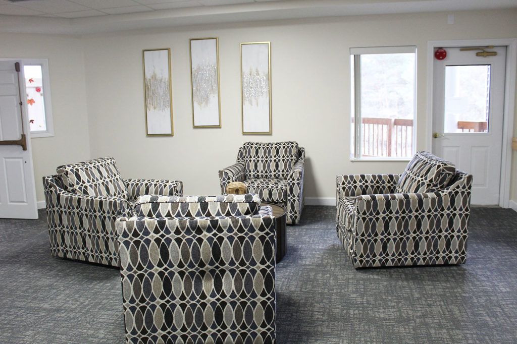 A modern living room with patterned armchairs and minimalist wall art.