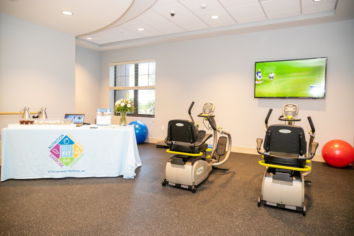 A fitness center room with exercise bikes and a television on the wall.