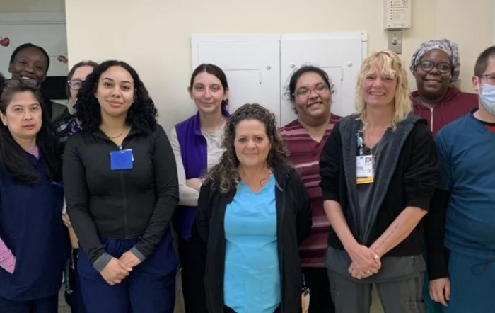 A group of women standing together in an office environment, smiling for the camera.