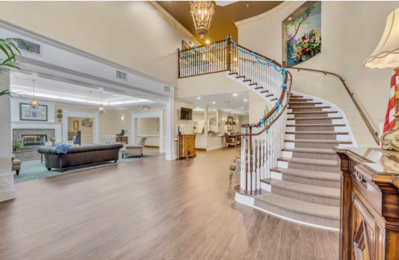 A spacious and modern lobby featuring a grand staircase, elegant chandelier, and contemporary artwork.